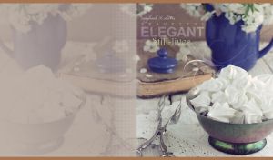 Metal candy box with meringue cakes, a book and a teapot on pastel brown table