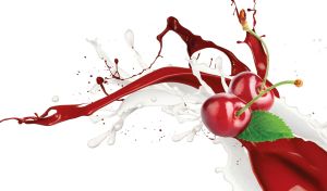 Fresh cherries in the splashes of milk and dark red liquid on a white backdrop