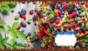 Close-up of a berry cake adorned with mint leaves on a light grey wooden table