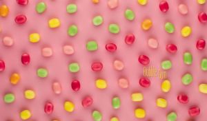 Vivid bubble gum drops scattered on a pastel pink backdrop