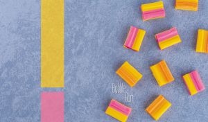 Assorted colorful bubble gums scattered across a textured grey-blue backdrop