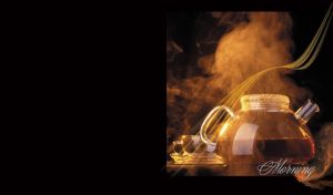 Glass kettle, half full of hot tea, in cloud of steam, glass cup and plate, on black
