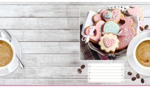 Heart-shaped pink cookies on a light gray wooden backdrop with a coffee cup