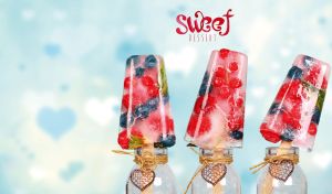 Berry popsicles in glass bottles against blurry pastel blue wallpaper