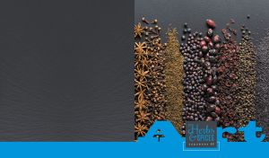 Arrangement of herbs and spices on a black tabletop with a blue footer