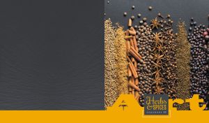 Arrangement of herbs and spices on a black tabletop with a dark yellow footer