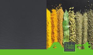 Arrangement of herbs and spices on a black tabletop with a green footer