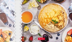 Delicious pancakes with fresh berries and sauces on a white textured backdrop