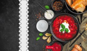 Beet soup with sour cream and fresh basil on a black textured backdrop