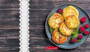 Cheese pancakes with raspberries and mint on a dark wooden-textured backdrop