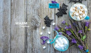 Overhead shot of cocoa drink and flowers arranged on a wood-textured backdrop