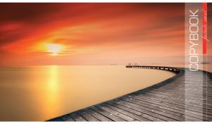 A long curved wooden pier against the orange-red sunset