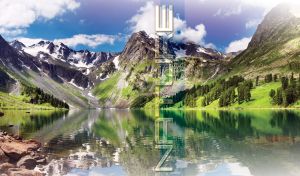 Snowy mountains and green foothills reflected in the blurry waters of a lake