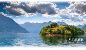 House on a island in the middle of a mountain lake against the blue summer sky