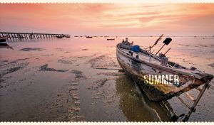 Summer landscape of an old thai boat on the wet sand at a yellow-pink sunset