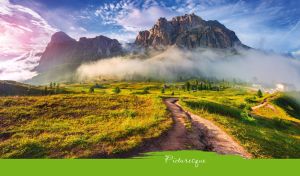Picturesque view of a dirt road at the foot of a misty mountain under a blue sky