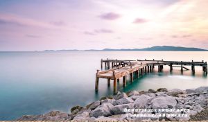 Panoramic view of a wooden pier in a milky haze at a purple-pink dawn