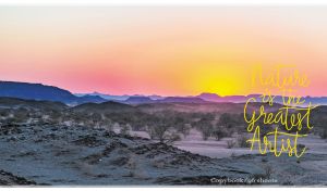 Panoramic desert scenery set against a mountain range at a yellow-pink dawn