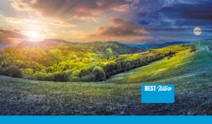 Lush valley at dawn with golden sun and full moon in gradient sky