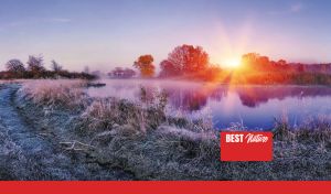 Sunrise in a violet sky over misty river and frosty grass