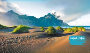 Majestic misty mountain range by the sea against a pastel blue sky