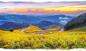 Winding road through a valley, set against the silhouettes of mountains at dusk