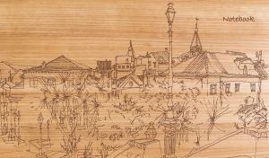 Wood burning art depicting a town sketch on a wooden backdrop
