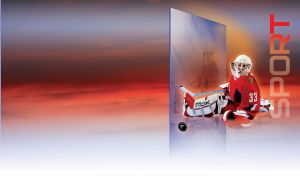 Hockey goalkeeper in red and white uniform sits in front of a glass pane