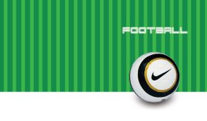 White football with black and golden circles on a green striped backdrop