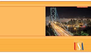 The Oakland Bay Bridge in San Francisco at night on a yellow-orange backdrop