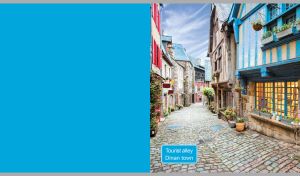 An atmospheric cobblestone alley in old Dinan town on a light blue backdrop
