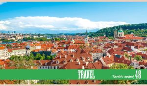 The red roofs and green hills of Prague under the light blue sky
