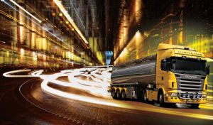 Yellow tanker truck drives in the light of skyscrapers leaving high-speed lights behind