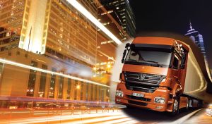 Orange truck drives through the night city in the bright lights of skyscrapers