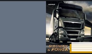 Green-grey truck moves fast on a highway under a bridge against a cloudy sunset